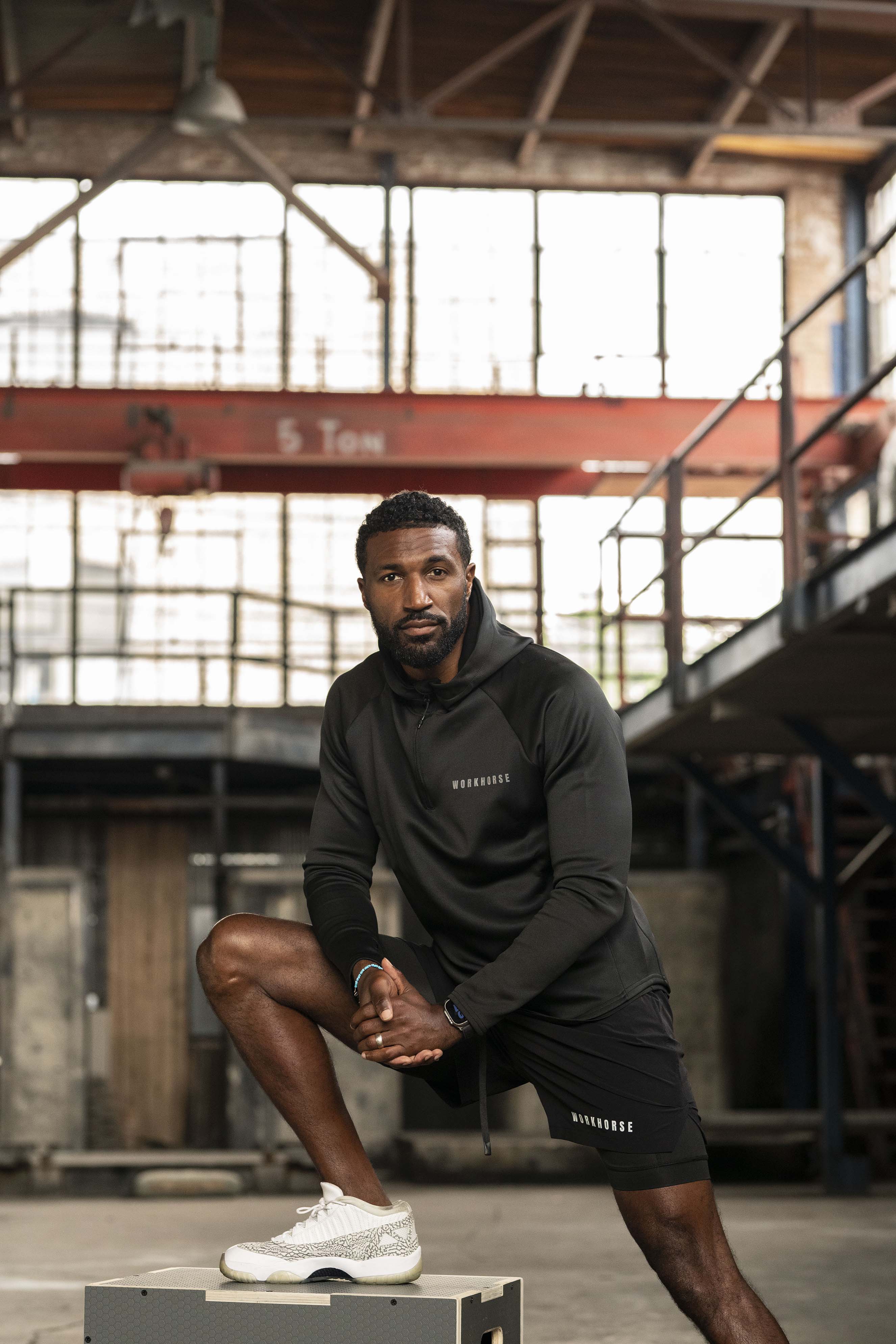 Man in black athletic wear posing in an industrial setting