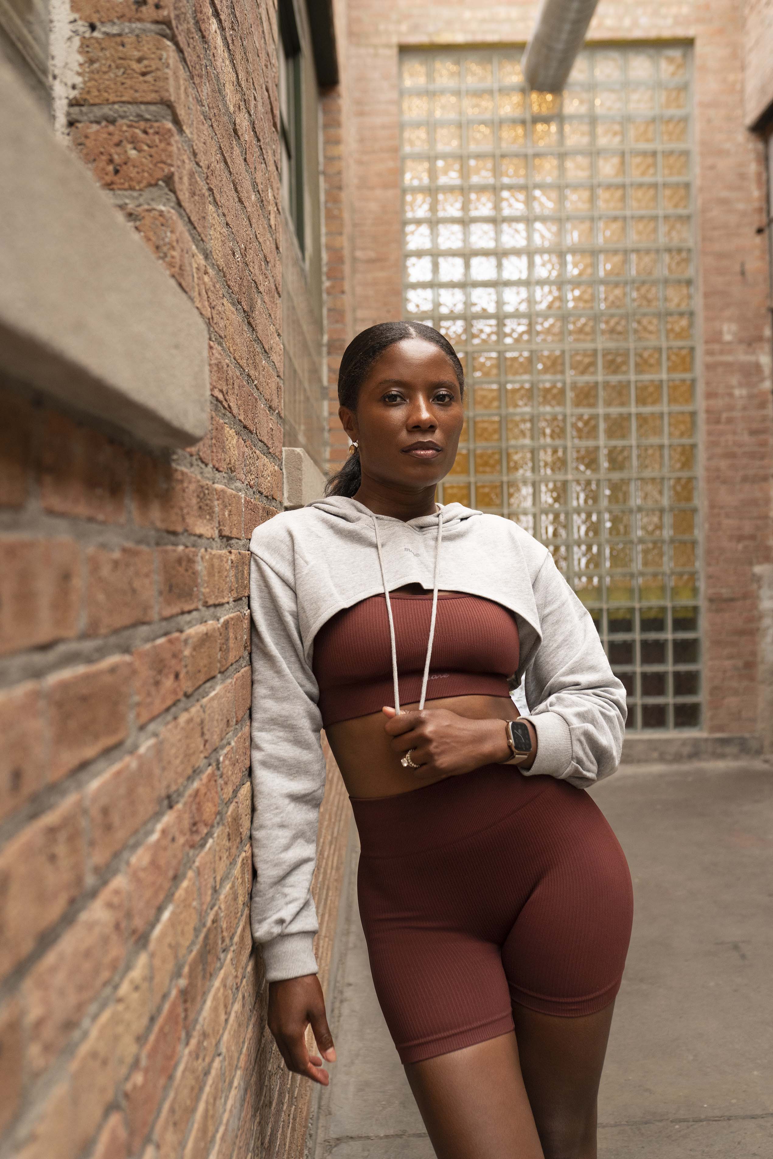 Woman in athletic wear leaning against a brick wall
