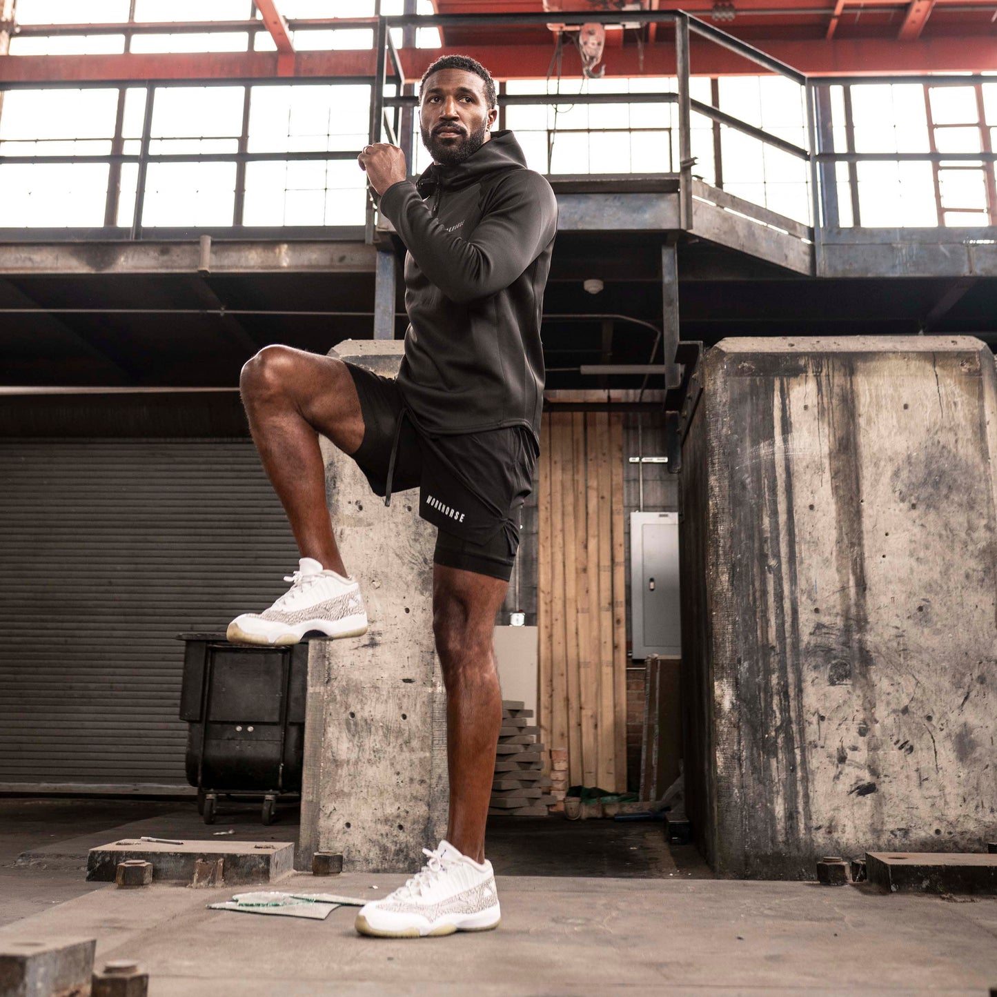 Model wearing Power Sport shorts in black posing in an industrial setting