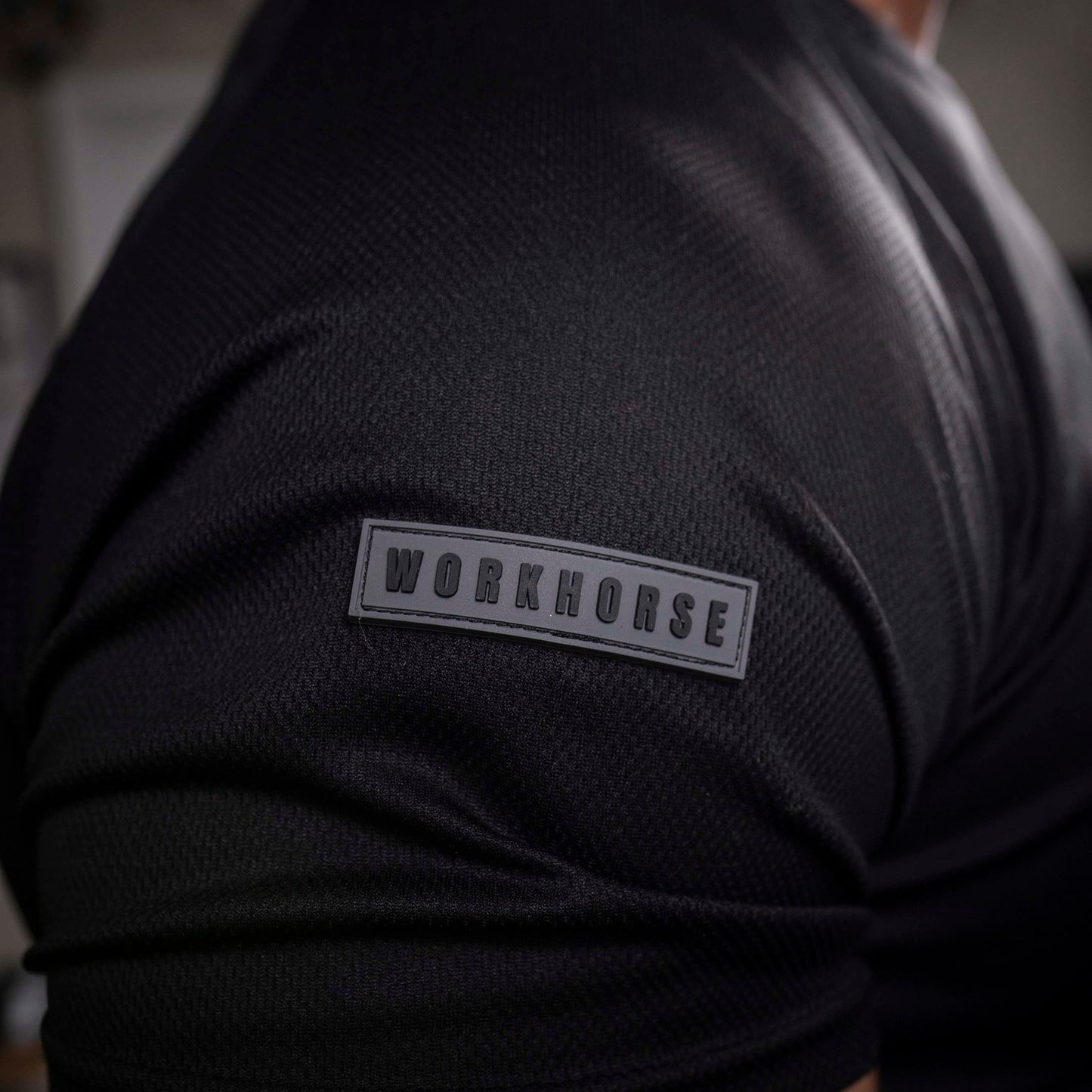Model wearing Workhorse's Black Sport Performance T-Shirt with 'Workhorse' patch on the right sleeve.