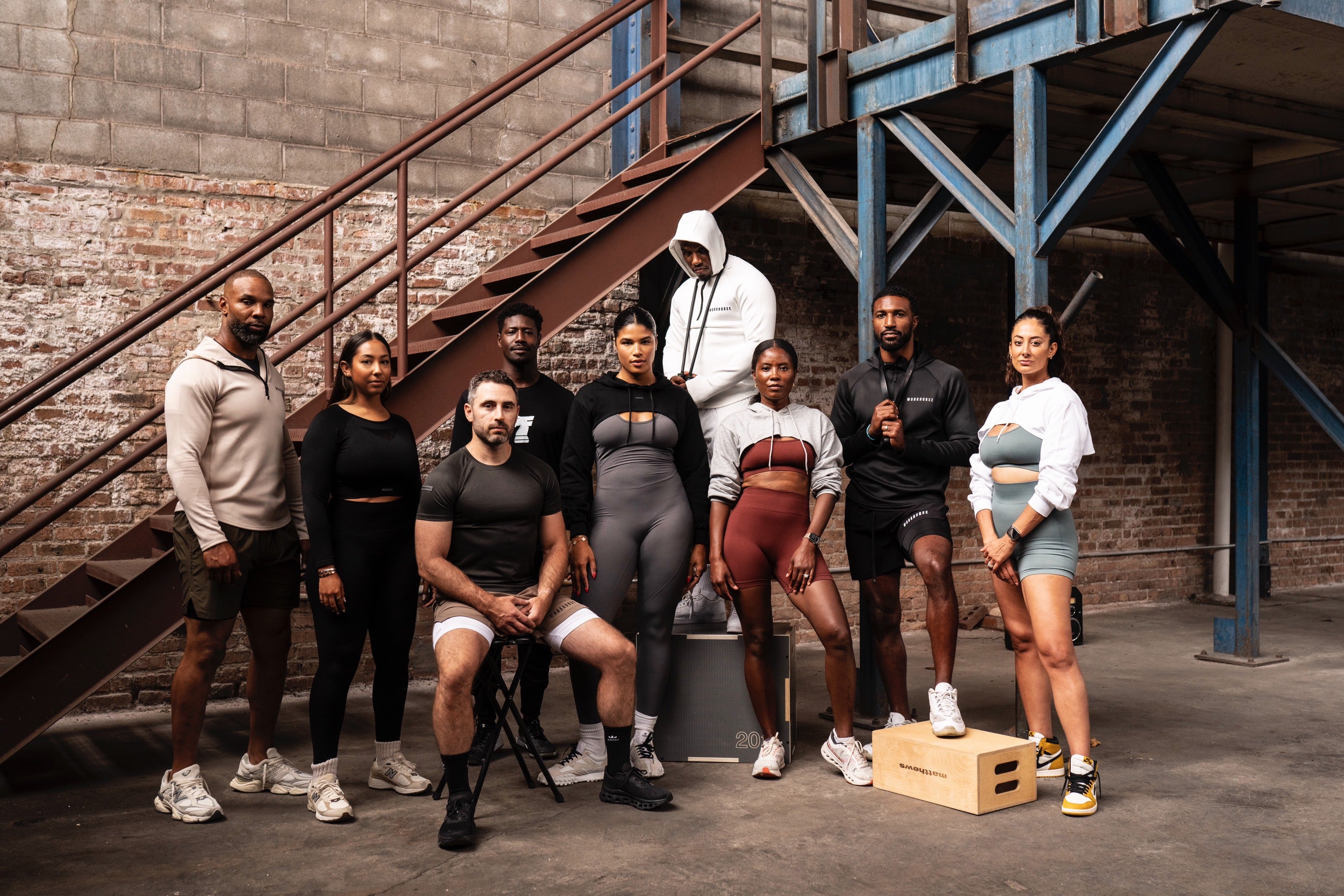 Group of athletes wearing Workhorse and Mare athleisure and performance apparel in a modern industrial setting.