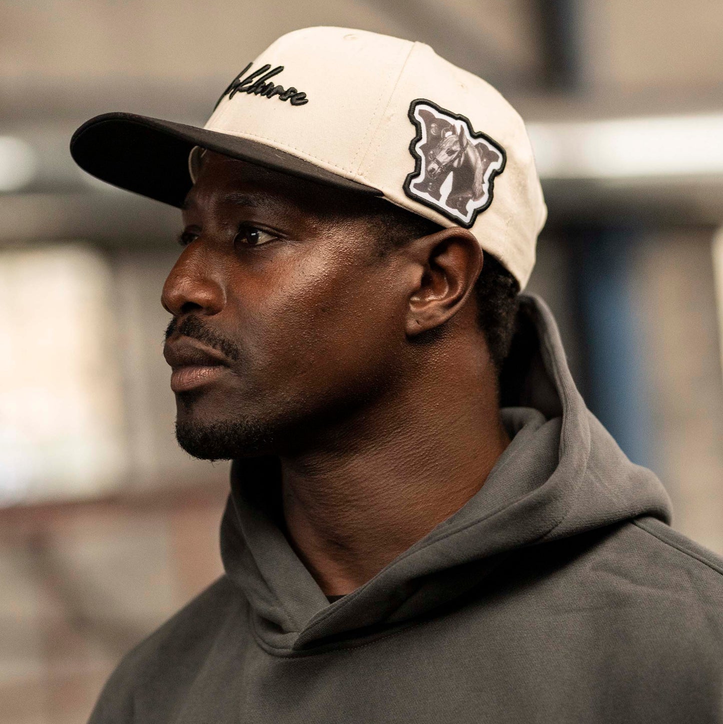 Model wearing Workhorse Legacy Hat in ivory color with Workhorse lifestyle script logo and a gray hoodie.