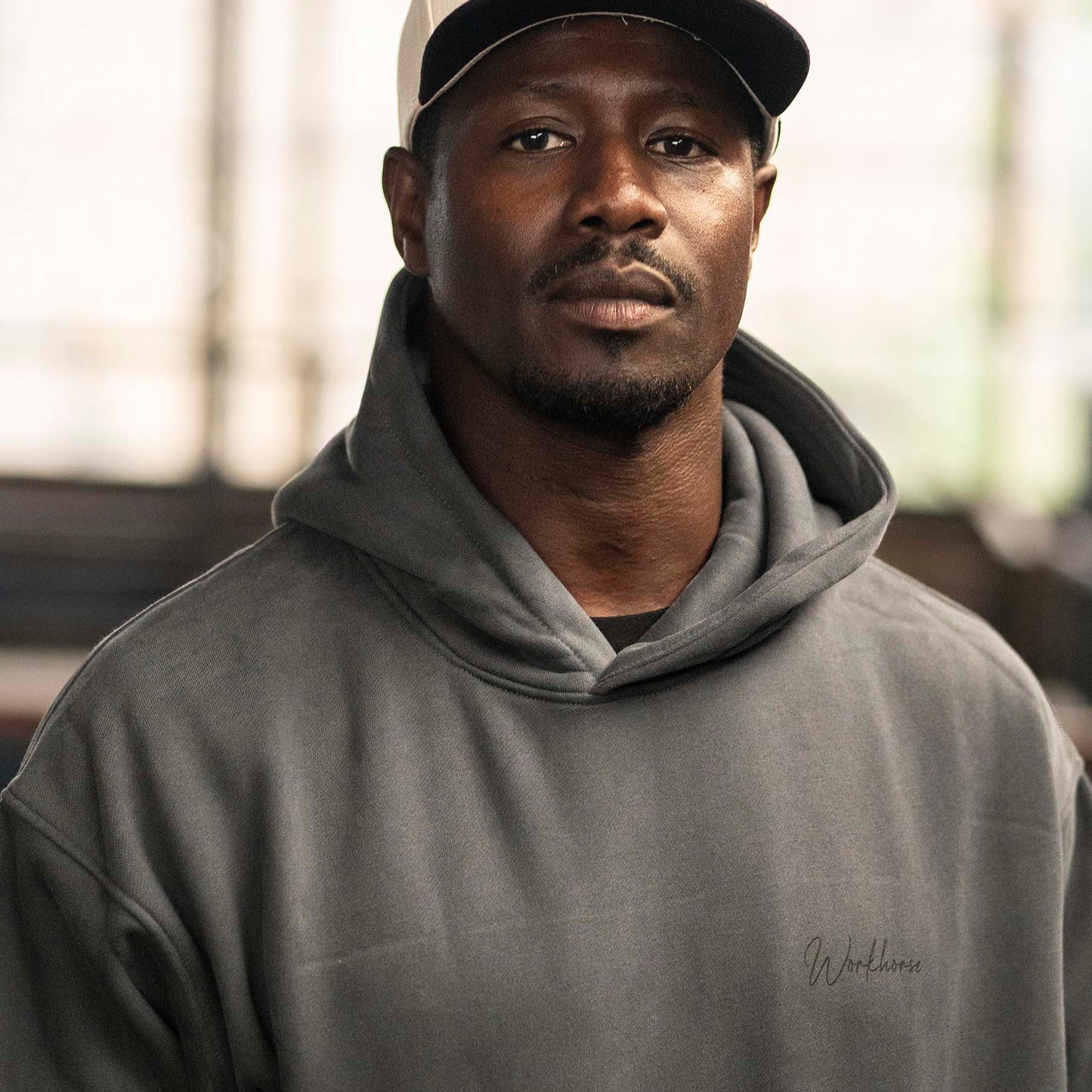 Model wearing Workhorse's Oversize Hoodie in color gray with the lifestyle Workhorse logo.