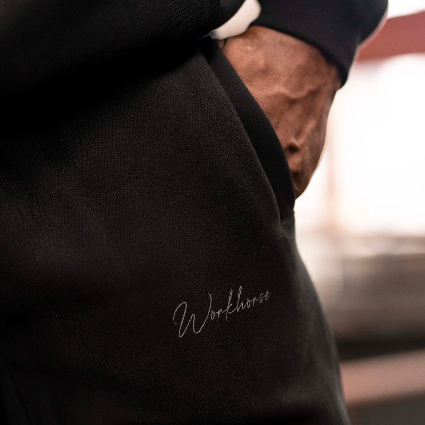Person wearing Workhorse Wide Leg Fleece Pants in black with the lifestyle Workhorse logo.