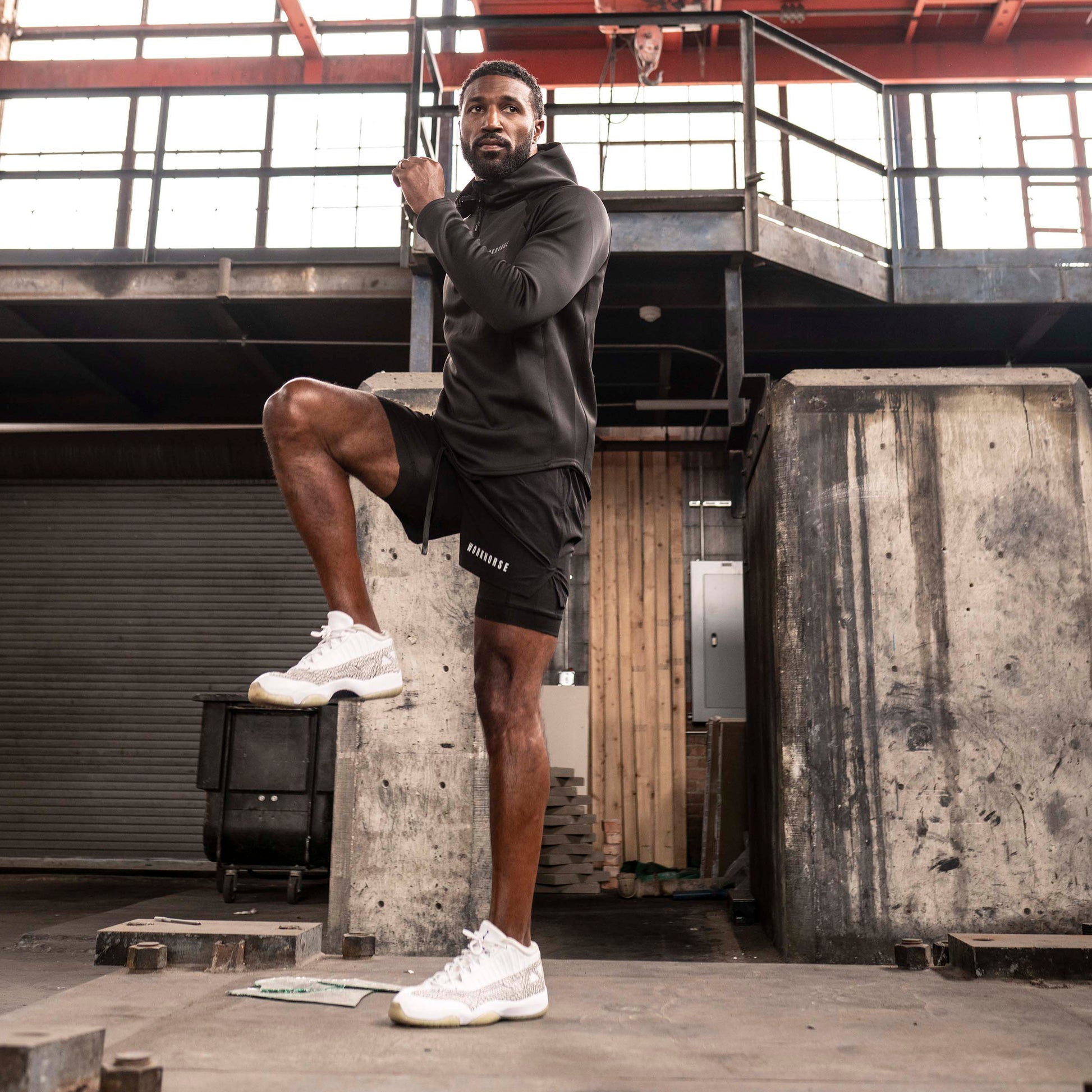 Model wearing Power Sport shorts in black posing in an industrial setting